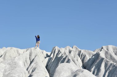 Yeni turistik yerleri keşfet, macera seyahatleri, Kireçtaşı dağının tepesinde duran kadın, açık mavi gökyüzüne karşı, minimal stil..