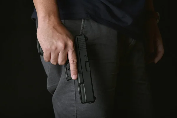 Man holding gun close to the body, Killer with 9mm handgun pistol waiting for robbing the victim, Weapon and violence crime concept.A