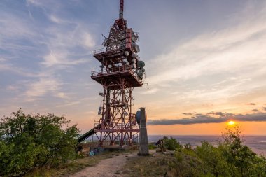 Küçük tepe üzerinde gün batımı sırasında verici Kulesi anten