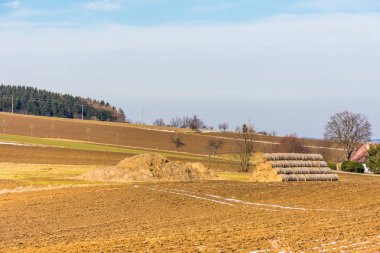 Saman balya ve gübre kırsal alanda. Bahar alanlar ve tarım için hazırlık. Tipik çek kırsal arazi, ağaçlar ve mavi gökyüzü