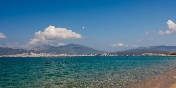El avión vuela por encima de la playa de Córcega. Ajaccio ciudad en el fondo, con montañas de Córcega . — Foto de Stock
