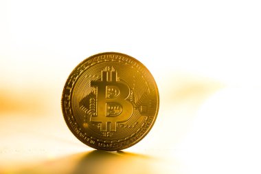 Altın bitcoin sikke günbatımı ışığında beyaz zemin üzerine yerleştirilir. Sanal para birimi simgesi