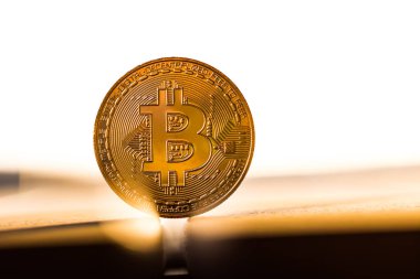 Altın bitcoin sikke günbatımı ışığında beyaz zemin üzerine yerleştirilir. Sanal para birimi simgesi