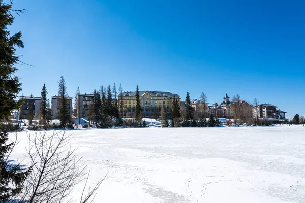 Slowakei: strbske pleso resort, Blick auf den zugefrorenen See im Winter und Hotelresort darüber. blauer Himmel. — Stockfoto