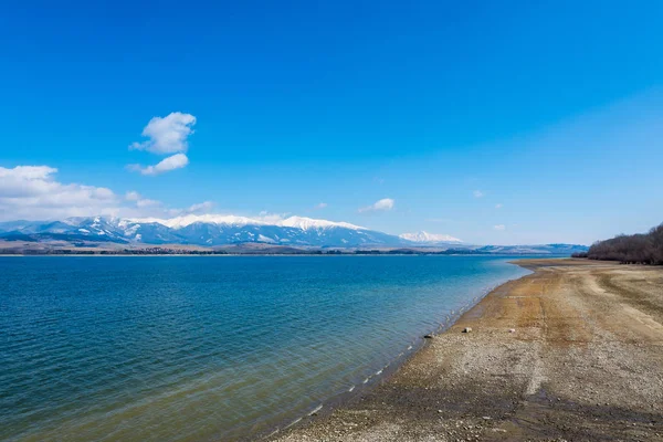 Eslovaquia: Pequeño pueblo cerca de la montaña Tatra. Lago Liptovska Mara en primer plano. Montaña de invierno y nieve . — Foto de Stock