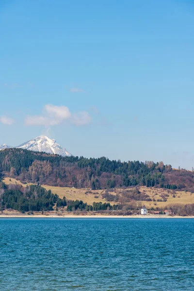 Eslovaquia: Pequeño pueblo cerca de la montaña Tatra. Lago Liptovska Mara en primer plano. Montaña de invierno y nieve . — Foto de Stock