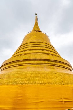 Altın şapşal ve melek heykeli olan Wat Saket tapınağı. Tayland 'ın Bangkok şehrinde Budizm sembolü. Görkemli ve Tayland kültürünün din sembolü. Bulutlu hava