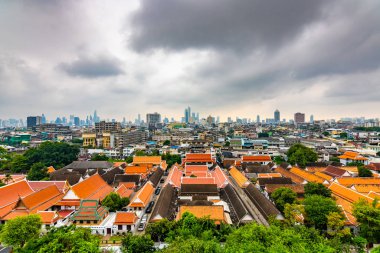 Tayland 'ın Bangkok şehrinin Panorama manzarası. Şehirdeki yerleşim yerleri ön planda, tapınaklar, gökdelenler ve modern binalar. Taze ağaçlar ve bitkiler. Bulutlu hava, dramatik bulutlar.