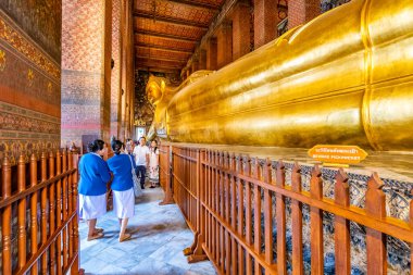 Bangkok, Tayland - 2.11.2019: Turistler Bangkok, Wat Pho tapınağındaki yalancı Buda heykelinin fotoğrafını çekiyorlar. Tapınak binasına büyük altın bir heykel yerleştirildi. Manevi Budizm yeri.
