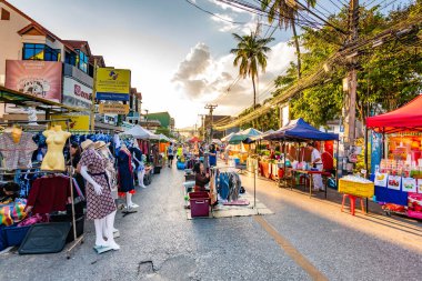 Chiang Mai, Tayland - 3.11.2019: Günbatımından kısa bir süre sonra Chiang Mai şehrinde gece pazarı. Turistler yolda yürüyorlar. Yandaki tezgahta Taylandlı satıcılar var. Hatıralar ve sokak yemekleri, yaz günü.