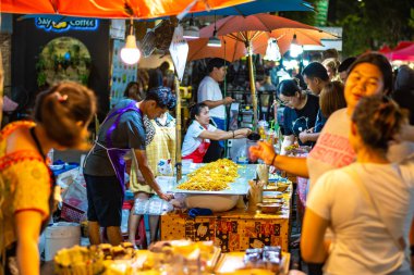 Chiang Mai, Tayland - 3.11.2019: Chiang Mai şehrinde kadınlar sokak yemekleri hazırlıyor. Pad Thai adlı ünlü Tayland yemeği turist tarafından sipariş edildi. Yumurta, erişte ve taze sebze.