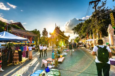 Chiang Mai, Tayland - 3.11.2019: Günbatımından kısa bir süre sonra Chiang Mai şehrinde gece pazarı. Turistler yolda yürüyorlar. Yandaki tezgahta Taylandlı satıcılar var. Hatıralar ve sokak yemekleri, yaz günü.