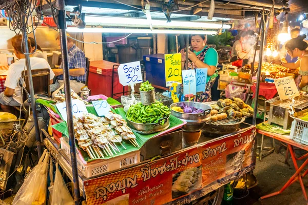 CHIANG MAI, TAILANDIA - 3.11.2019: Las mujeres preparan comida callejera en el mercado nocturno de la ciudad de Chiang Mai. Famosa comida tailandesa llamada Pad Thai ordenada por el turista. Huevos, fideos y verduras frescas —  Fotos de Stock