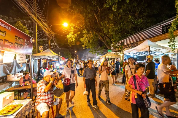 CHIANG MAI, TAILANDIA - 3.11.2019: Mercado nocturno en la ciudad de Chiang Mai poco después del atardecer. Turista están caminando en la carretera. Vendedores tailandeses en el puesto de al lado. Souvenirs y comida callejera, día de verano —  Fotos de Stock