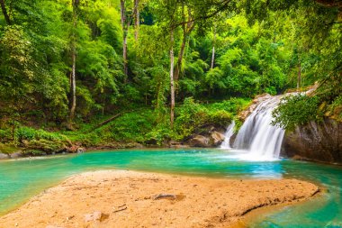 Beautiful waterfall Mae Sa, Thailand. Fresh and pure water stream is flowing on the rock stone ground in tropical rainforest. Fresh plants and trees above river. Vibrant colors in pure nature