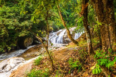 Beautiful waterfall Mae Sa, Thailand. Fresh and pure water stream is flowing on the rock stone ground in tropical rainforest. Fresh plants and trees above river. Vibrant colors in pure nature