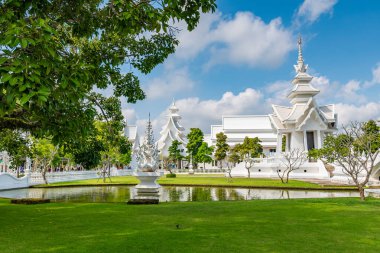 Tayland 'ın Chiang Rai şehrindeki Beyaz Tapınak (Wat Rong Khun). Cennete giden yolu, günahkarların lanetlenmiş ruhları üzerinde köprüsü olan güzel Budist antik binası. Ünlü turist merkezi. Mavi gökyüzü.