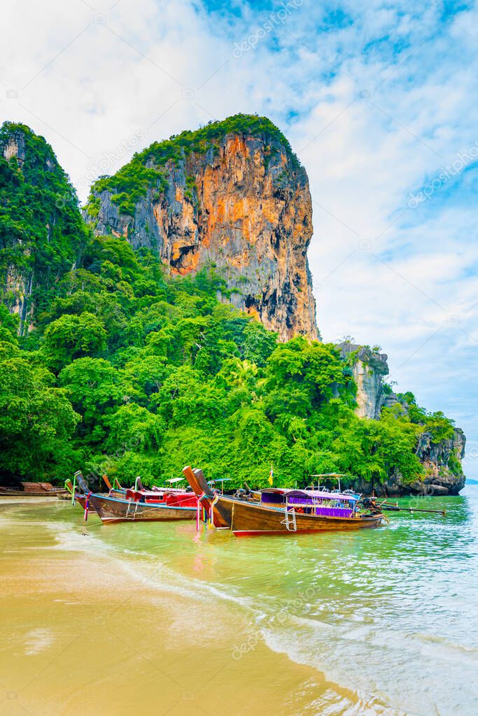 The famous Railay beach at Krabi, Thailand. Long tailed boats are prepared for passengers near limestone rock. Tropical paradise, famous tourist destination. Turquoise sea with white sand.