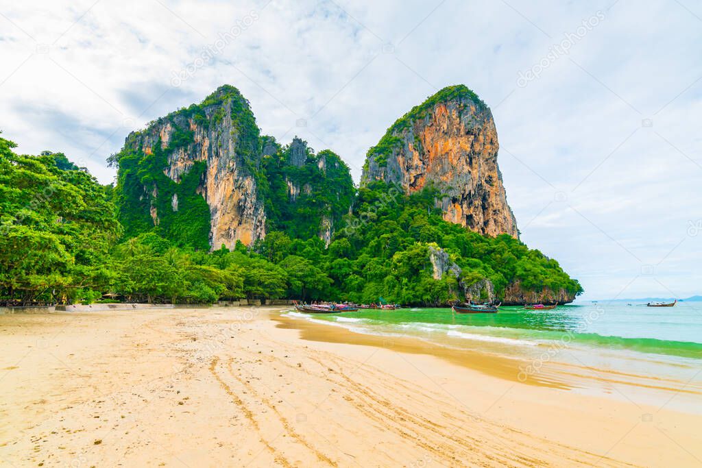 The famous Railay beach at Krabi, Thailand. Long tailed boats are prepared for passengers near limestone rock. Tropical paradise, famous tourist destination. Turquoise sea with white sand.