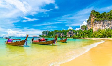 Tayland, Yengeç Kasabası 'ndaki Railay sahil koyundaki uzun teknelerin güzel manzarası. Tropikal cennette tatil için ünlü bir turizm merkezi. Güzel bir yaz günü. Büyük kireçtaşı tepesi ve kaya.