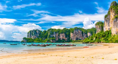Tayland, Yengeç Kasabası 'ndaki Railay sahil koyundaki uzun teknelerin güzel manzarası. Tropikal cennette tatil için ünlü bir turizm merkezi. Güzel bir yaz günü. Büyük kireçtaşı tepesi ve kaya.
