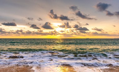 Denizin ya da okyanusun üzerinde güzel bir gün batımı. Canlı ve yumuşak renkler, sihirli ışık. Gökyüzündeki küçük bulutlar, sudaki güneşin yansıması ve kumsaldaki kum. Tropikal bölgelerde romantik zaman kavramı.
