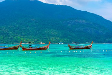 Tayland 'daki Ko Lipe adasında uzun kuyruk teknesi. Beyaz kum, sahil ve turkuaz deniz ile tropik ada Tarutao Ulusal Deniz Parkı 'nın bir parçasıdır. Idyllic tatil, cennette rahatlama.