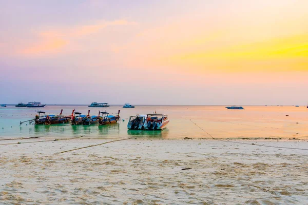 Magic sunset above small harbor with long tail boats at Ko Lipe island, Thailand. Tropical island is part of Tarutao national nature park. Soft light, concept of romantic evening in tropical paradise.