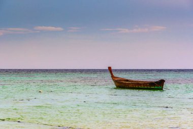 Tayland 'daki Ko Lipe adasında uzun kuyruklu tekneleri olan küçük liman, tropik fırtınadan kısa süre önce. Denizin üzerinde büyük ve ağır kara bulutlar. Tayland için tipik ahşap tekne detayları.