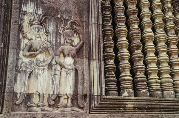 Bas-reliefs Devatas on wall of temple. Carved sandstone spindles in a window. Angkor - UNESCO World Heritage site. Cambodia, Siem Reap, Angkor Wat