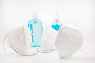 Alkol el yıkama jeli ve beyaz arka planda beyaz virüs maskesi..