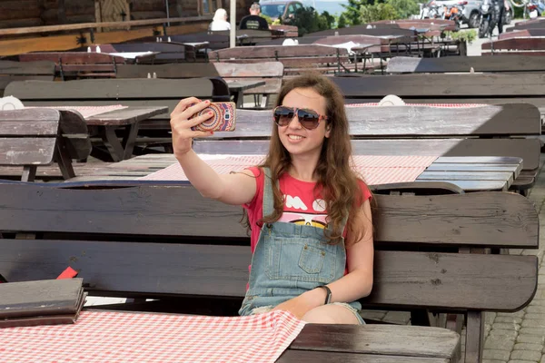 Young girl doing selfie in sunglasses on the terrace of a cafe — Stock Photo, Image