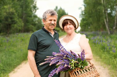 sepet ve buket çiçek mor lupines, orman parkta yaşlı çift portresi
