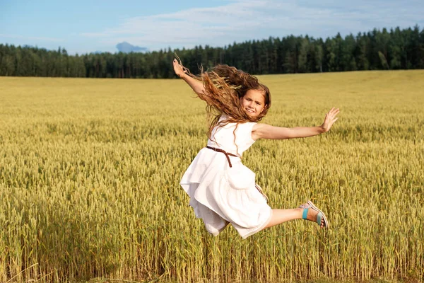 Дівчина в польоті зі стрибка на пшеничному полі влітку — стокове фото
