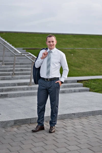 Portrait of a young serious smiling businessman in grey blue suit — Stock Photo, Image