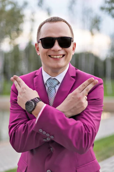 Portrait comique d'un jeune homme d'affaires en costume rose blague montre pistolets avec les doigts — Photo