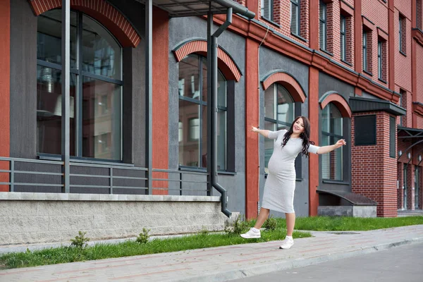 Молодая беременная женщина танцует вдоль городских окон — стоковое фото