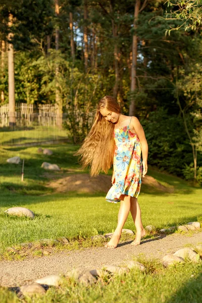 Молода дівчина гуляє в парку босоніж на світлому сонці в літньому сарафані — стокове фото
