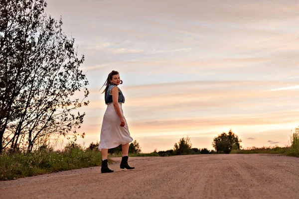 Молодая цыганка, идущая по дороге на закате — стоковое фото