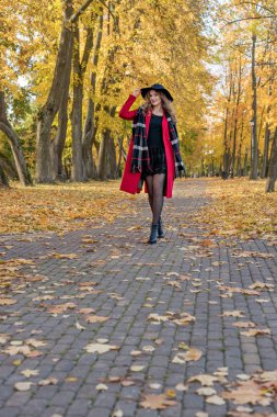 Kırmızı paltolu bir kız sonbahar park ormanda yürür