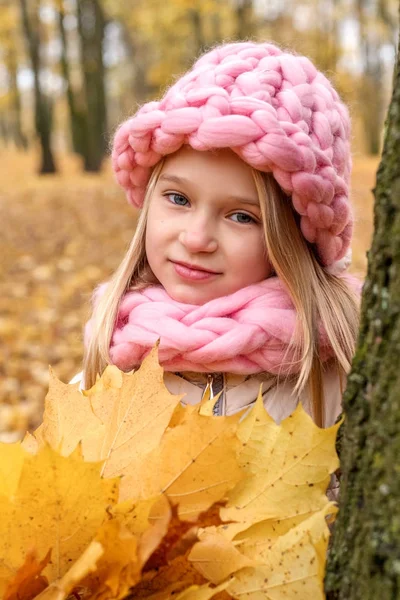Сновидіння стомлена дівчина в шарфі і кепка грубого рукоділля з букетом кленового листя стоїть спираючись назад на дерево — стокове фото