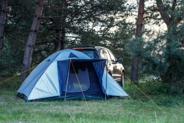 bir arabaya ormandaki bir çadır ile göl kıyısında akşam zam