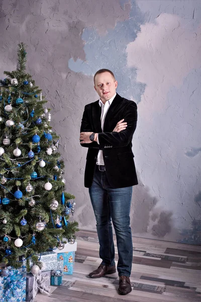 ライフスタイルの服を着た魅力的な男がクリスマスツリーの近くに立っています. — ストック写真