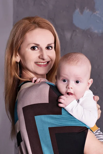 Ritratto di una giovane madre in abito con il suo bambino in braccio ad una festa — Foto Stock