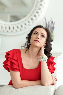 Düşünceli rüyalarda genç ve çekici bir esmer kadının portresi kırmızı elbiseli bir sandalyenin arkasına yaslandı.
