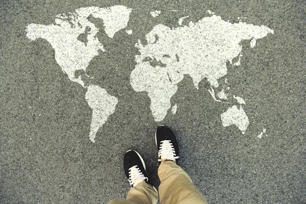 Dünya harita üzerinde bir asfalt yol. Üstten Görünüm bacaklar ve ayakkabı. POV
