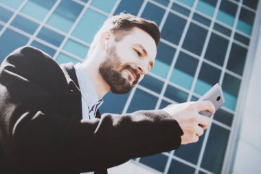 Memnun sakallı adam sokakta yürüyor ve kablosuz kulaklık müzik dinler