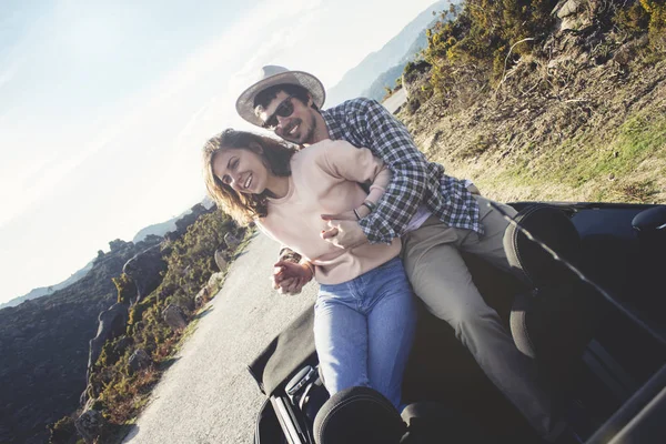 Young couple in casual clothes rest and have fun on the back seat of a gig. They travel on a warm summer day on a cabriolet over picturesque mountain road — Stock Photo, Image