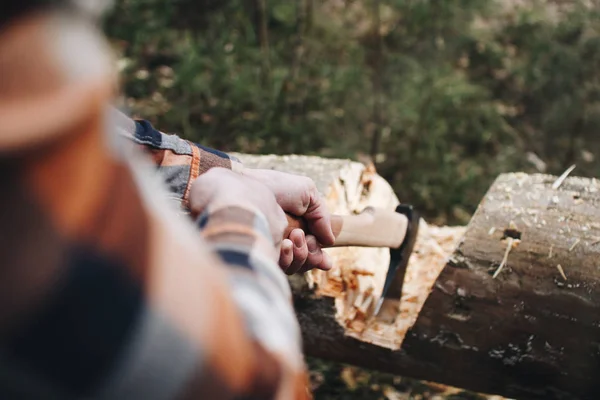 Strong lumberjack in a plaid shirt and an ax in hands is going to cut a tree in the forest — Stock Photo, Image