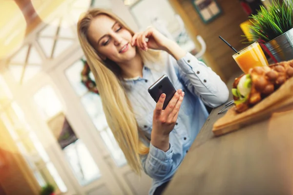 Mulher bonita verifica notícias nas redes sociais em seu telefone em um café acolhedor no estilo de Provence — Fotografia de Stock